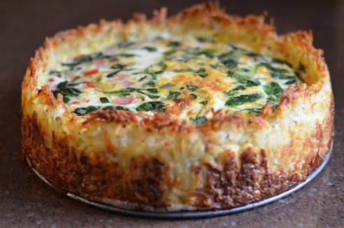 a quiche with cheese and spinach on top