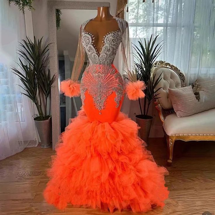 a mannequin with an orange and silver dress on display in a living room