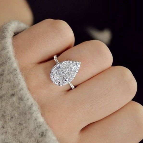 a woman's hand with a diamond ring on top of her finger and an engagement ring in the middle