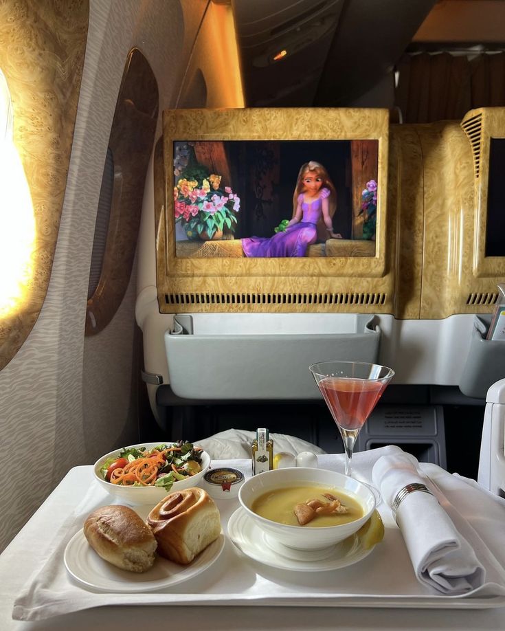 a tray with food and drinks on top of it next to an airplane seat in the background