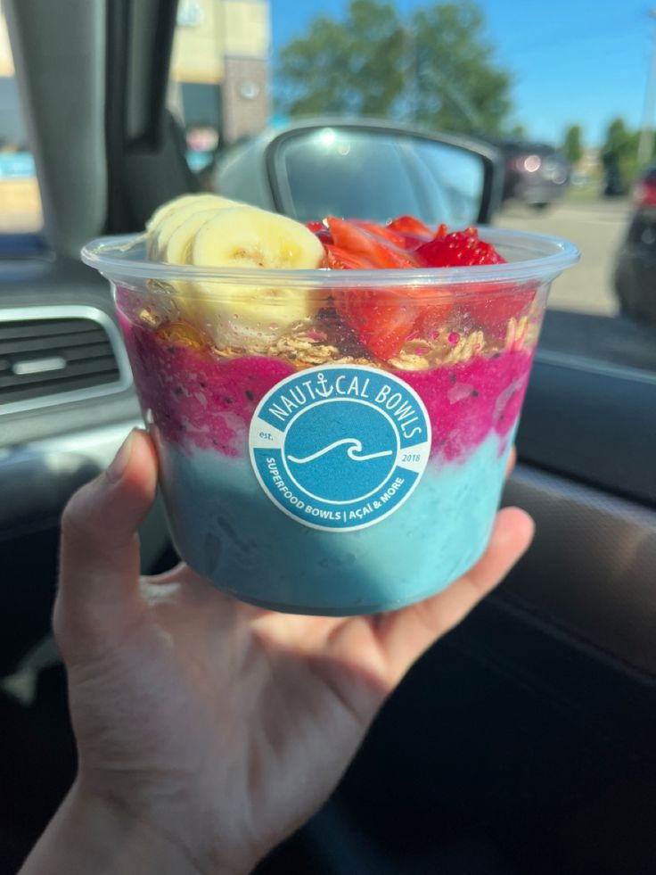 a person holding up a bowl of food in their hand while sitting in a car