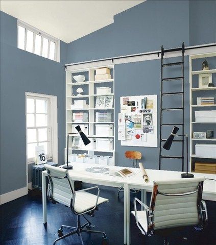 an office with green walls and white desk in the center, along with two chairs