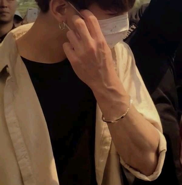 a woman wearing a face mask talking on her cell phone while standing in a crowd