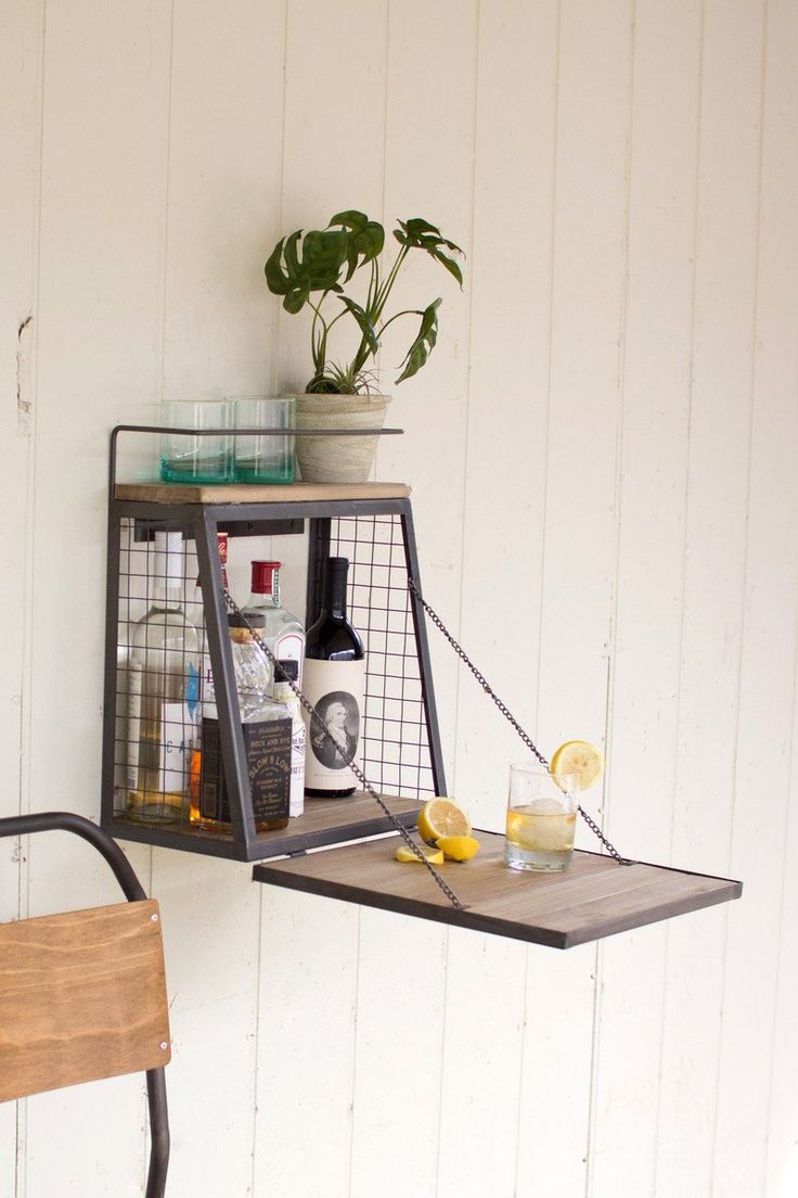 two metal shelves with drinks on them against a white wall and a wooden chair in front