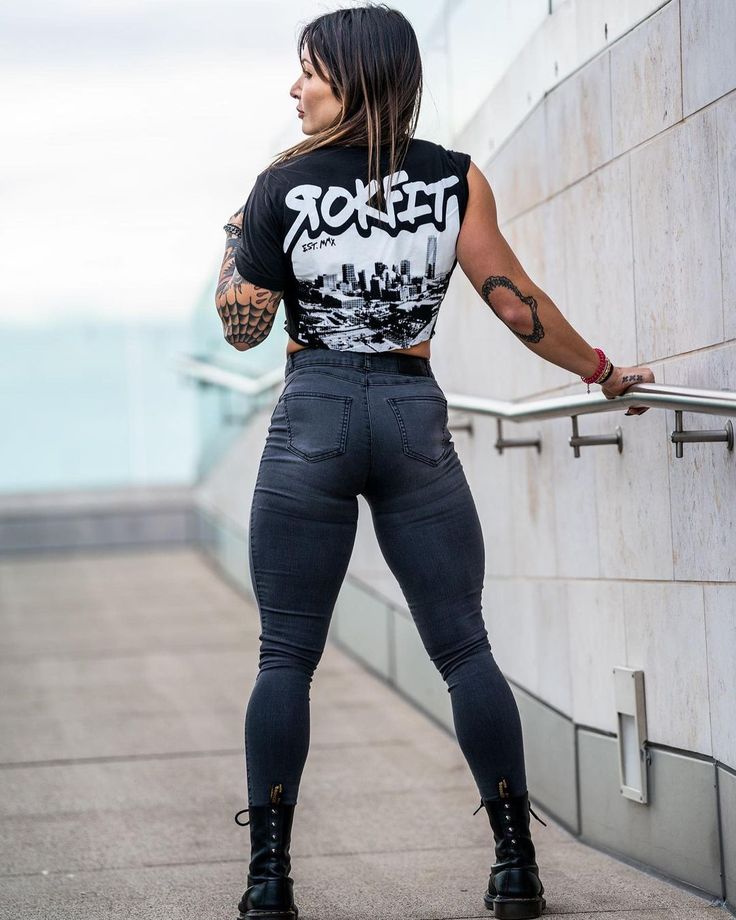 a woman leaning against a wall with her back to the camera and wearing black jeans