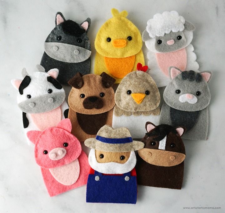 there are many felt animals on the table together, including one wearing a hat and another with an animal's head