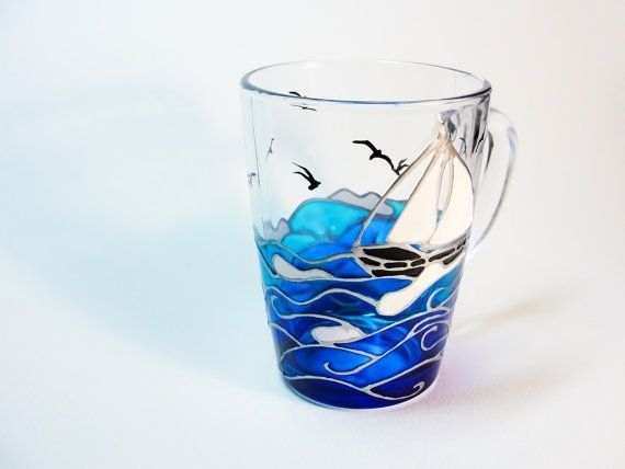 a glass mug with a sailboat painted on the side and seagulls flying above it