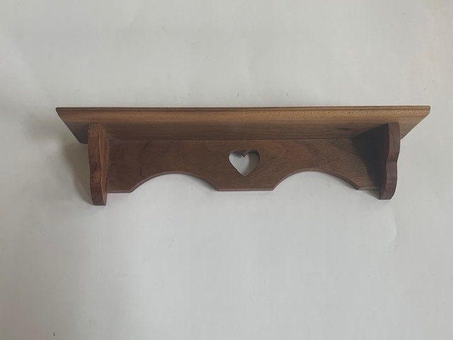 a wooden shelf with a heart shaped hole in the middle on a white wall background