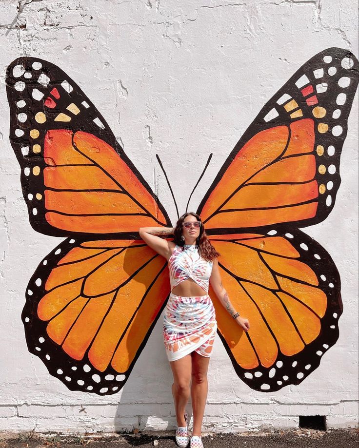 a woman standing in front of a painted butterfly