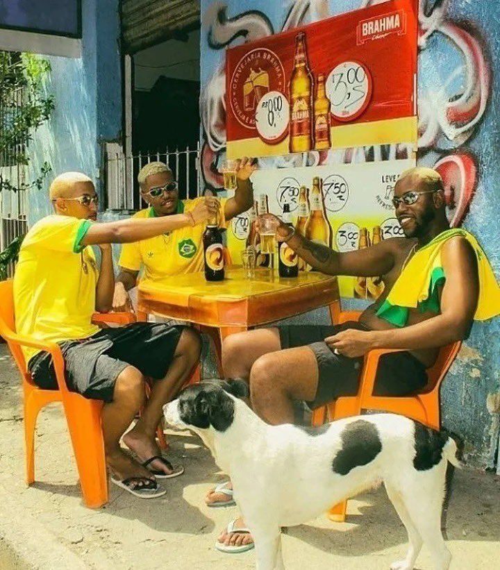 three men sitting at a table with a dog in front of them