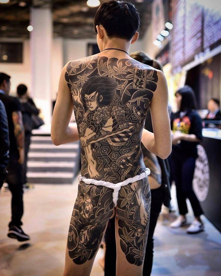 a man with tattoos on his back standing next to other people