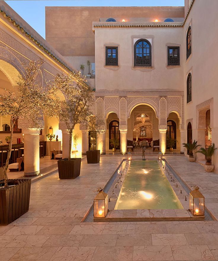 an indoor swimming pool surrounded by potted plants and candles in the middle of a courtyard