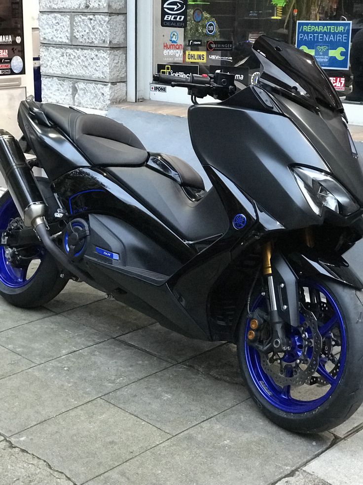 a black and blue motorcycle parked on the sidewalk