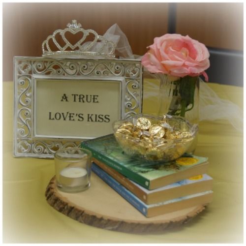 there is a small vase with flowers on top of books and a sign that says a true love's kiss