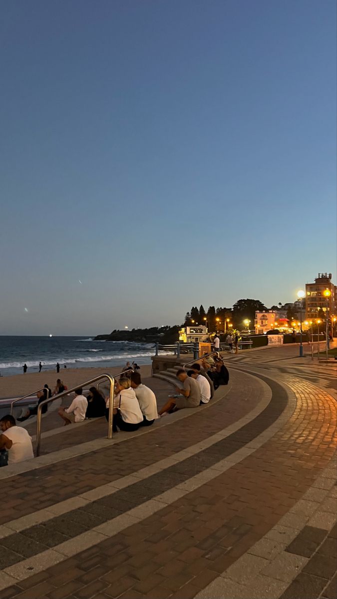 several people sitting on benches near the ocean