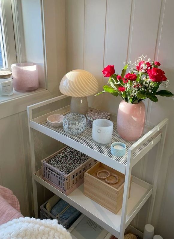 a white shelf with flowers and candles on it