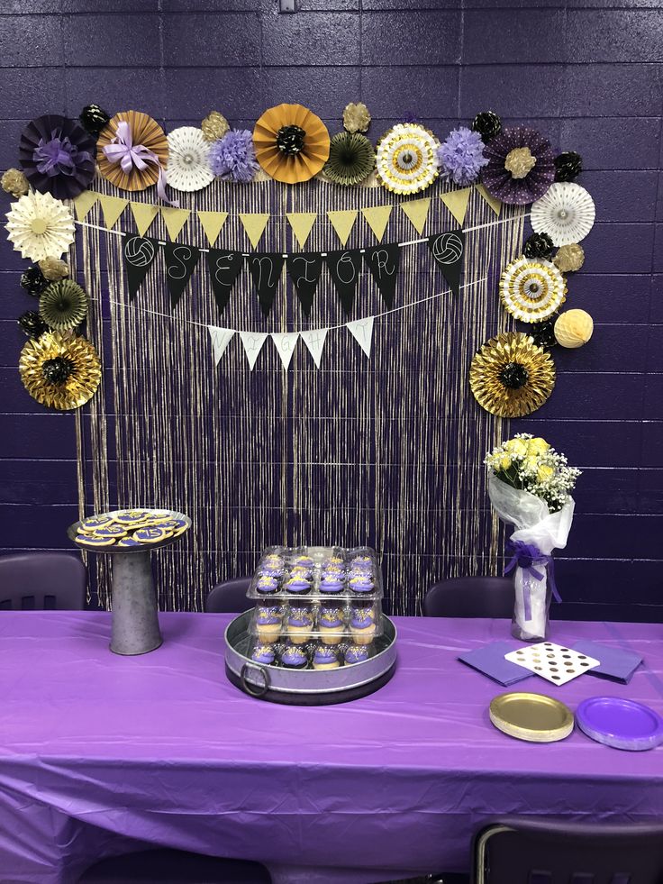 a purple table topped with cake and cupcakes