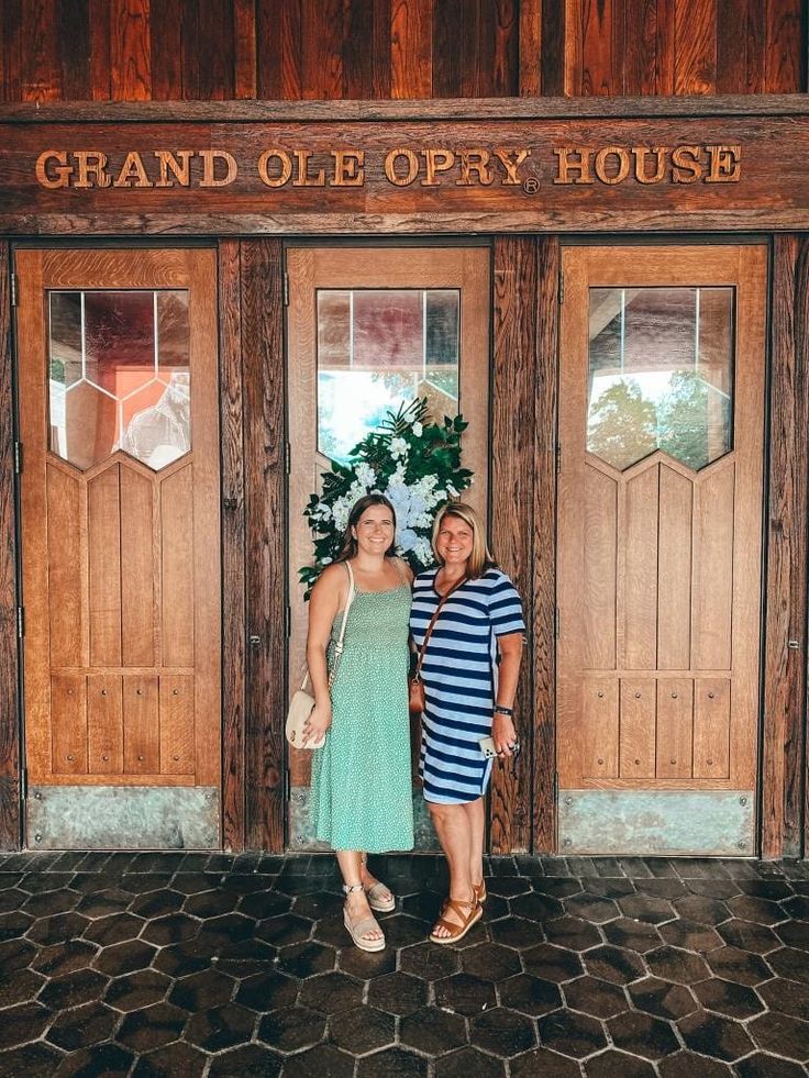 two women standing in front of a grand olee opry house