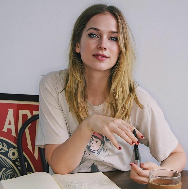 a woman is sitting at a table with an open book and a glass of coffee