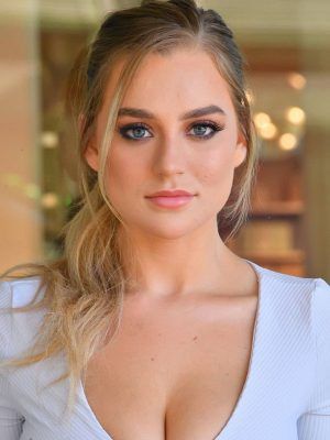 a close up of a woman with very large breast wearing a white top and blue eyeshadow