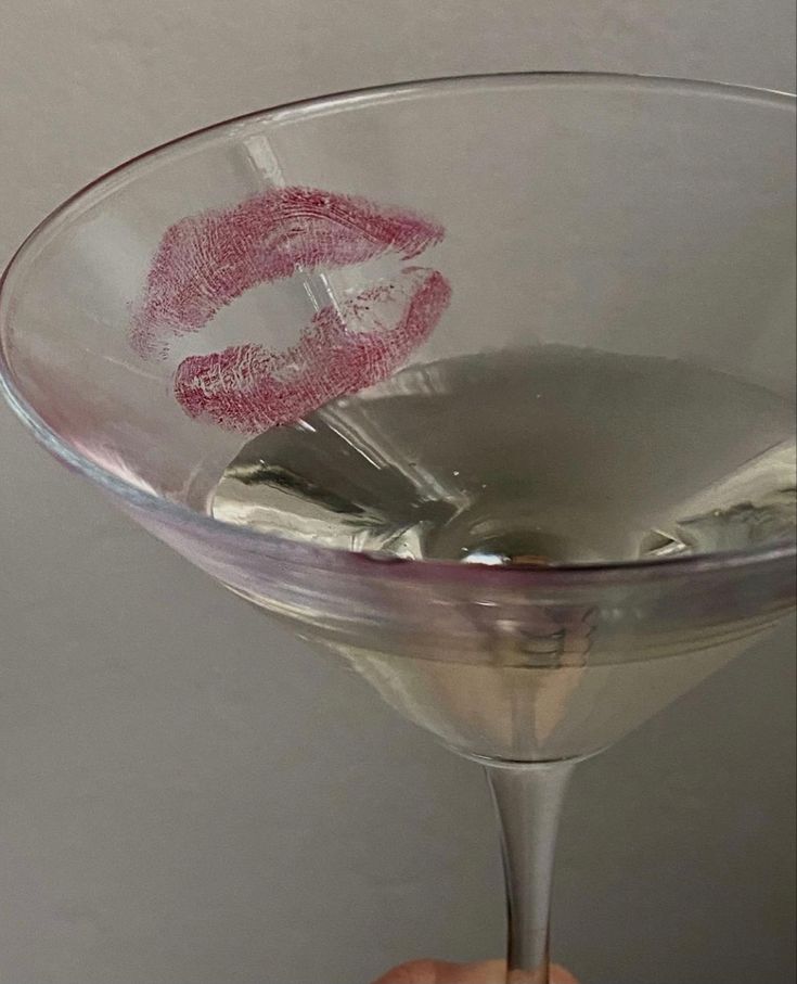 someone holding up a martini glass with lipstick drawn on it