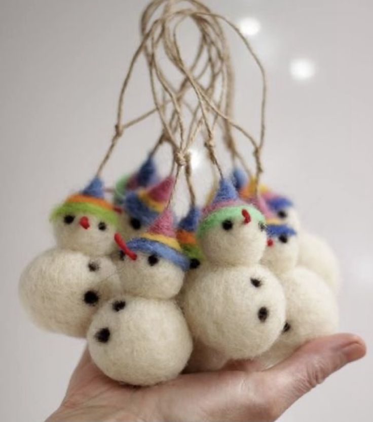 a hand holding some small white balls with snowmen on them, hanging from a string