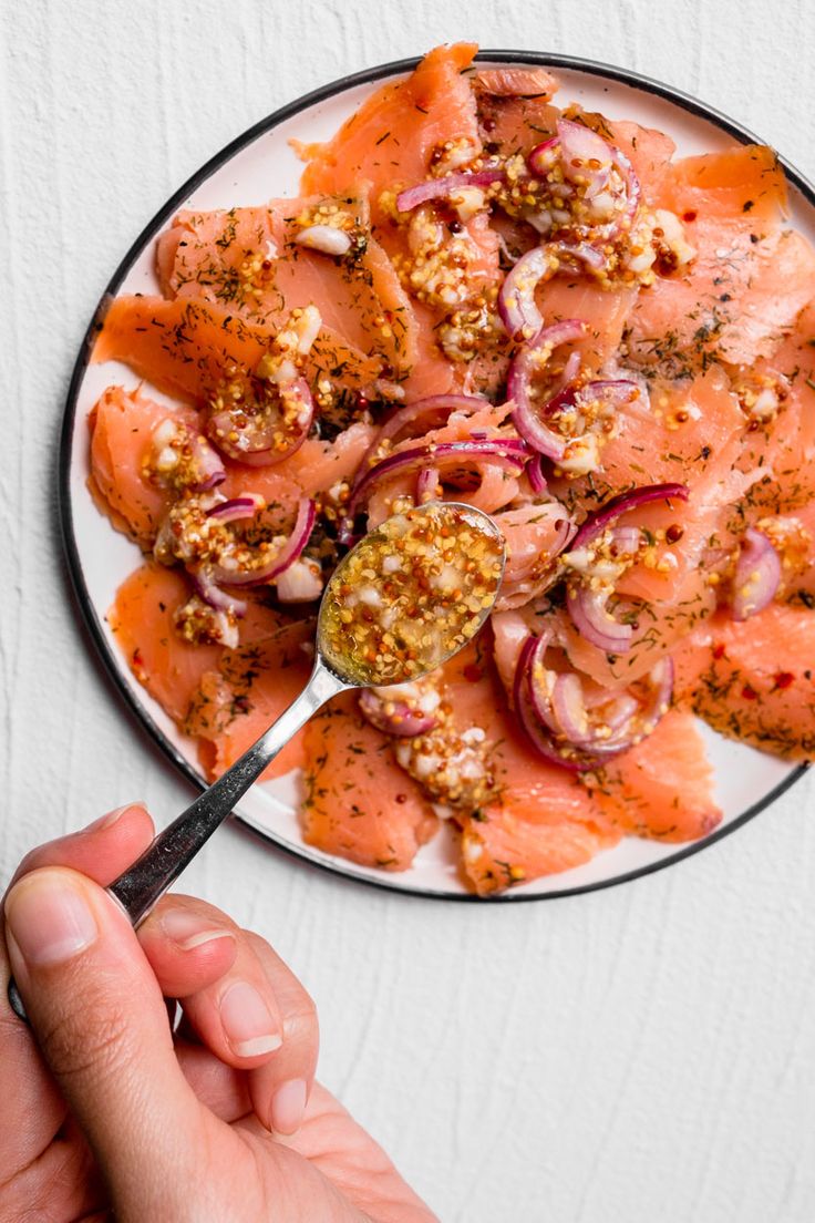 a plate with salmon and onions on it being held by a person's hand