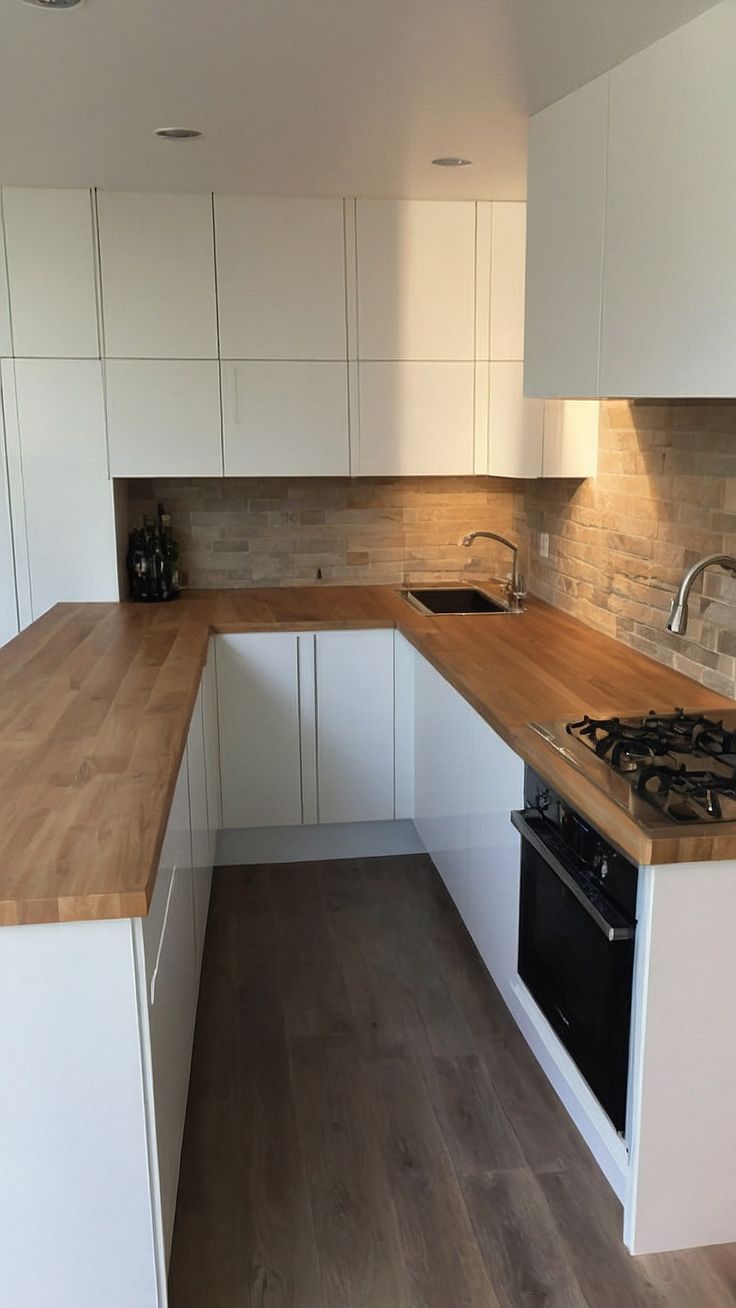 an empty kitchen with white cabinets and wood counter tops