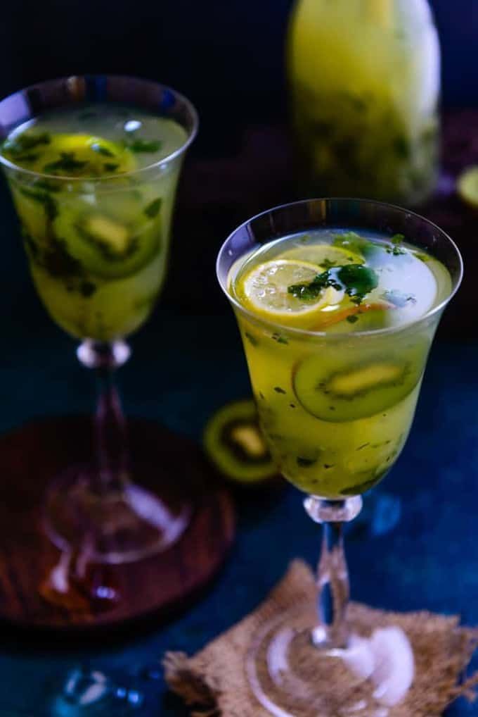 two glasses filled with green liquid on top of a table