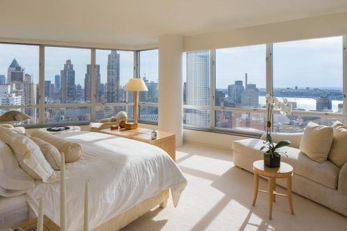 a bedroom with large windows overlooking the city