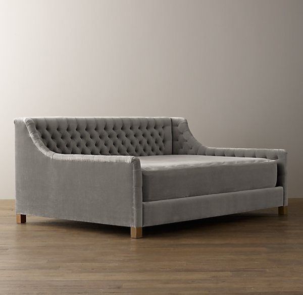 a gray couch sitting on top of a hard wood floor next to a white wall