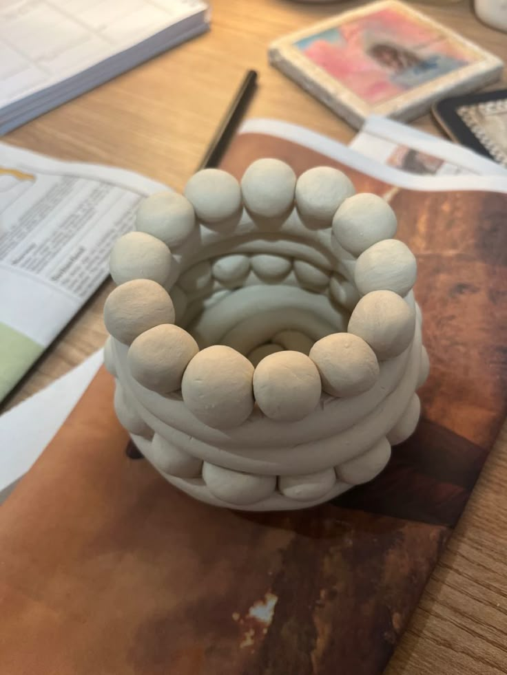 a white vase sitting on top of a wooden table next to papers and pencils