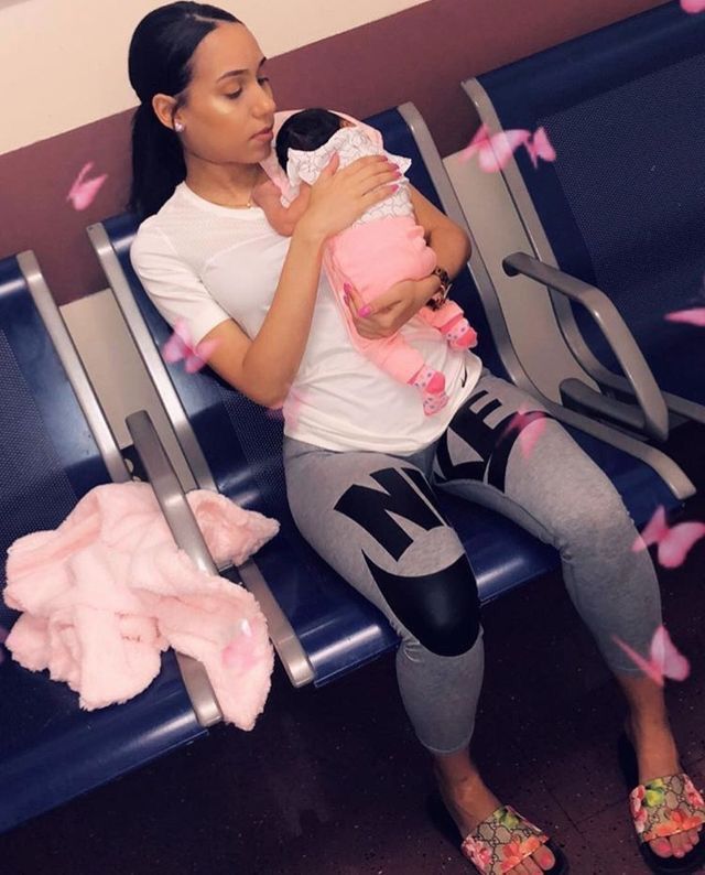 a woman holding a baby in her arms while sitting on an airport bench with pink confetti