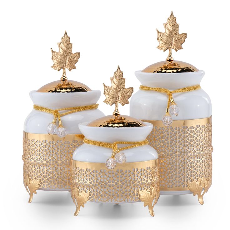 three white vases with gold leaf decorations on them