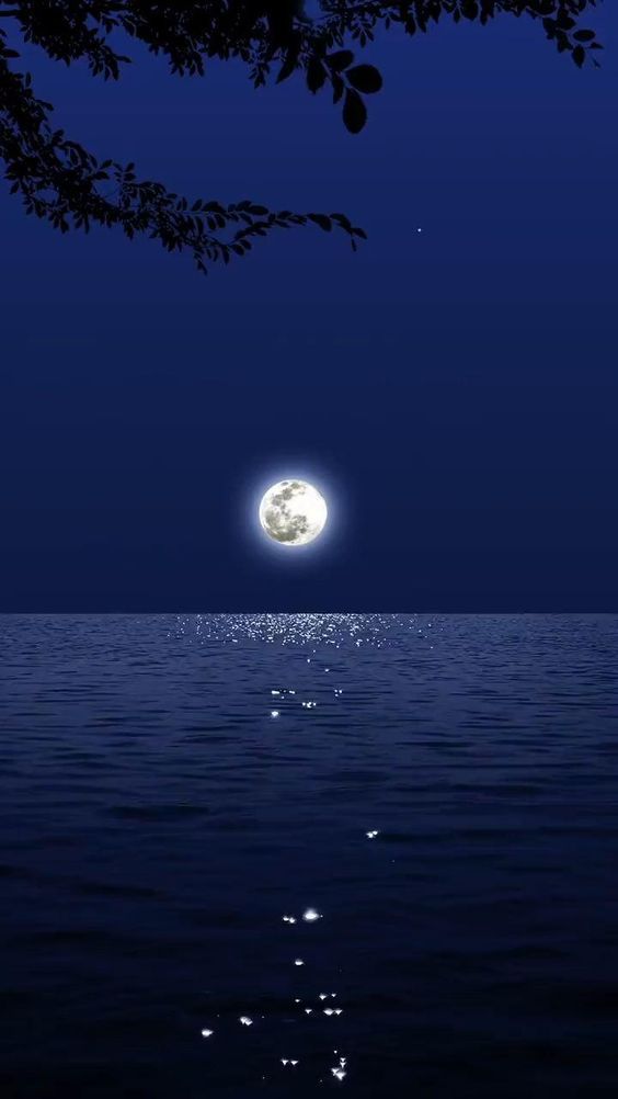 the moon is shining over the water and it looks like it's floating in the air