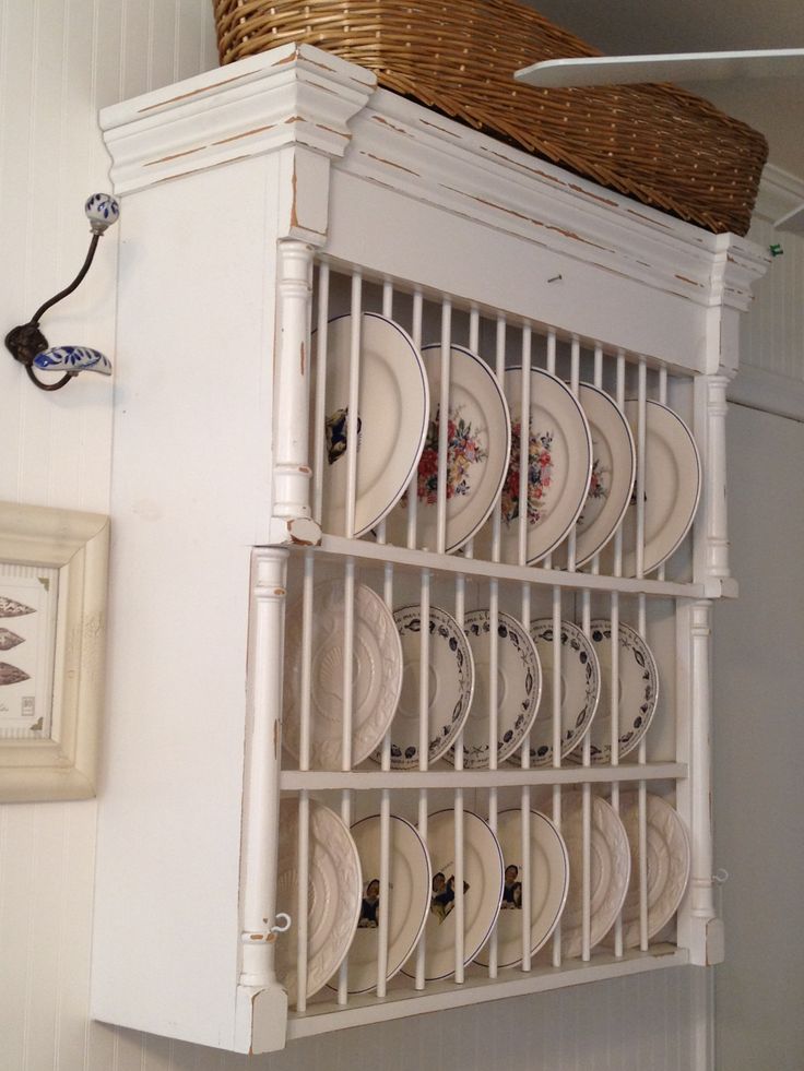 an old china cabinet with plates on it and a wicker basket hanging from the top