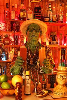 a man in a sombrero is making a drink at a bar with many bottles on the shelves