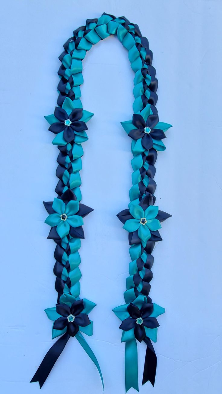 a blue and black ribbon with bows attached to the ends is hanging on a white wall