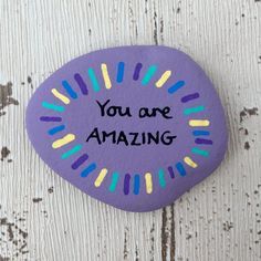 a purple rock with the words you are amazing painted on it