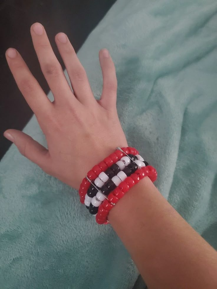 a person's hand wearing a red, white and black beaded wristband