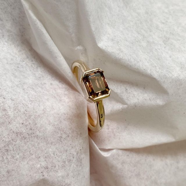 a close up of a ring on a white cloth with a black diamond in the center