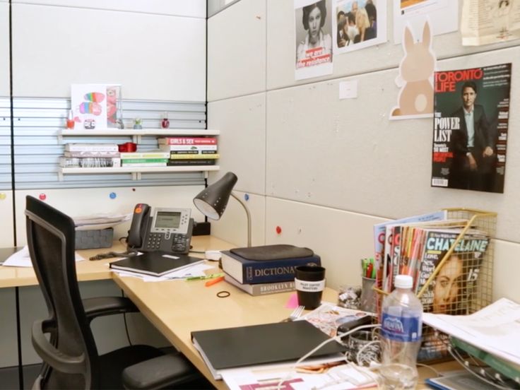 a desk with a phone, laptop and other office supplies on it in an office