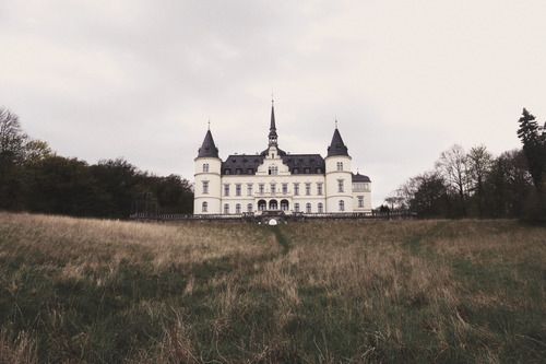 a large white building sitting on top of a lush green field