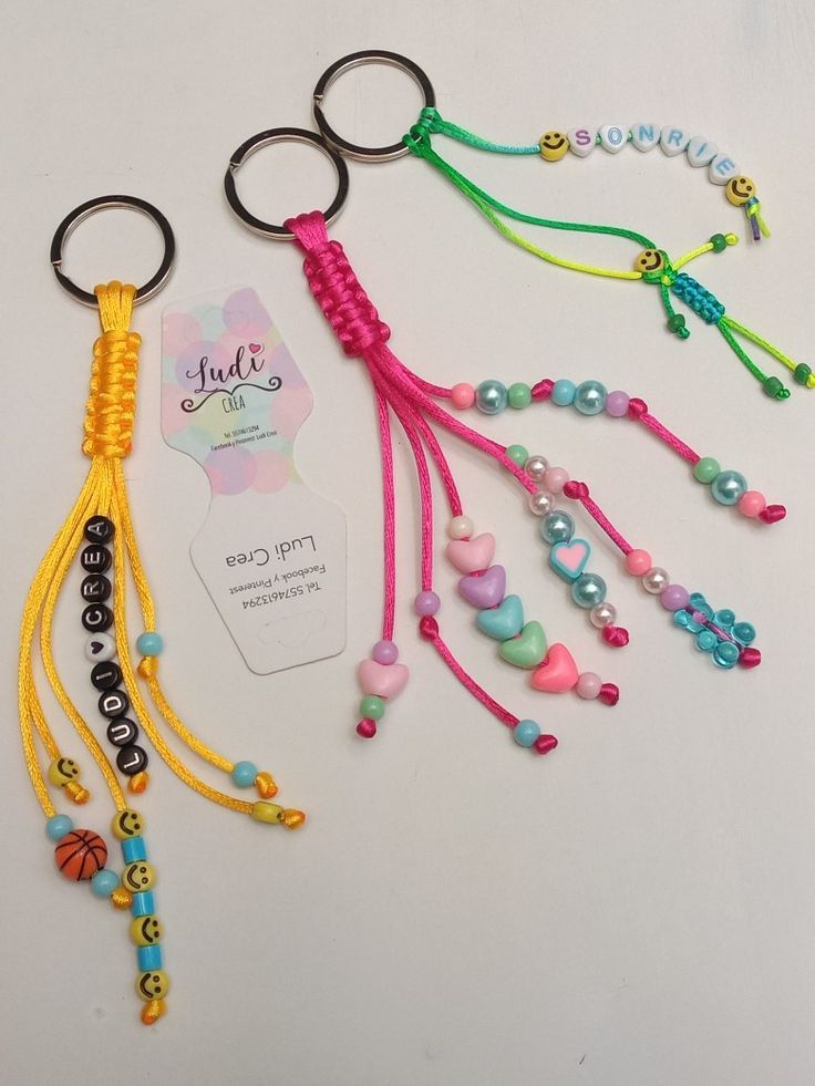 four key chains with beads and charms attached to each one on a white table top