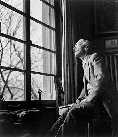 an old photo of a man sitting in front of a window looking out the window