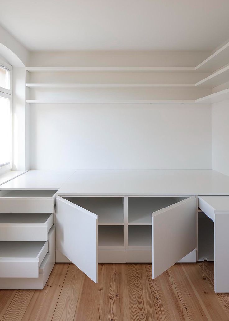 an empty room with white furniture and wood flooring