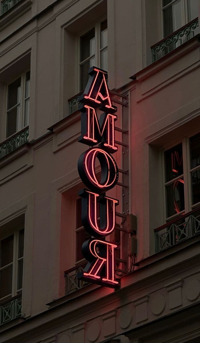 a neon sign that reads amour on the side of a building in paris, france