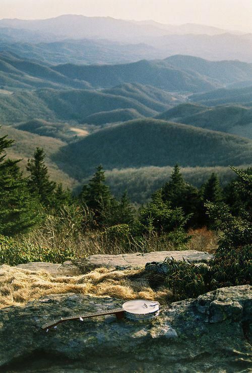 there are mountains in the distance with rocks and trees on it, as well as a frisbee