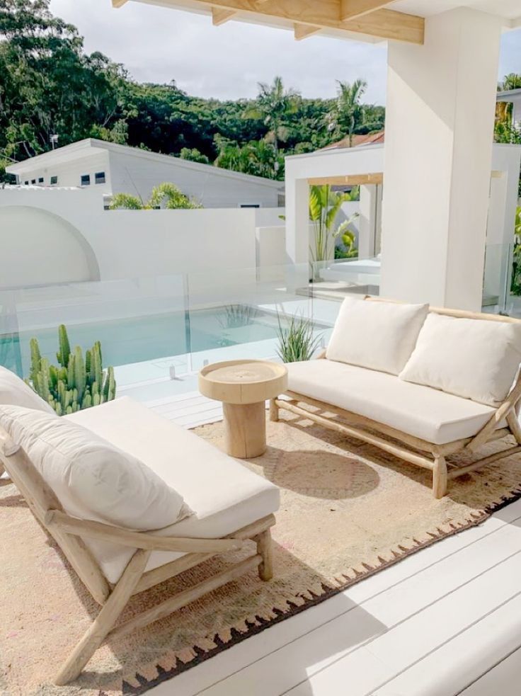 two lounge chairs sitting on top of a wooden floor next to a swimming pool in a house