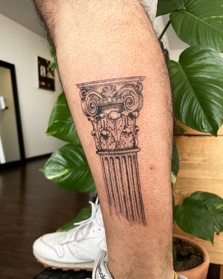 a man with a tattoo on his leg that has an image of a greek column